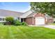 Inviting brick home with a two-car garage and a professionally landscaped lawn featuring mature shrubs and green grass at 1605 Leisure Way, Greenfield, IN 46140