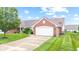 Beautiful brick home featuring a well-kept lawn, mature trees, and an attached garage at 1605 Leisure Way, Greenfield, IN 46140