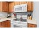 Close up of kitchen with white stove, above-range microwave, and wood cabinetry at 1605 Leisure Way, Greenfield, IN 46140