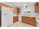 Functional kitchen with oak cabinetry, white appliances, and a window offering natural light at 1605 Leisure Way, Greenfield, IN 46140