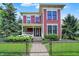 Charming red two-story home with a landscaped front yard, black fence, and a welcoming front porch with flowers at 2263 Glebe St, Carmel, IN 46032