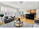 Bright living room with hardwood floors, a view to dining area, a kitchen bar, and a window with plantation shutters at 2263 Glebe St, Carmel, IN 46032