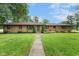 Beautifully landscaped front yard with a brick ranch-style house surrounded by mature trees at 2750 Chamberlin Dr, Indianapolis, IN 46227