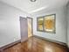 Empty bedroom with wood floors, boarded-up window, and open door for easy access to stairs at 3042 Newton Ave, Indianapolis, IN 46201