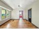 Open-concept living room with bright light from windows and hardwood floors needing some love at 3042 Newton Ave, Indianapolis, IN 46201