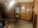 A living room with wood paneling and a doorway to another room in need of renovation at 3143 Carson Ave, Indianapolis, IN 46227