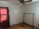 A bright bedroom features hardwood floors, a ceiling fan, and a window with translucent red curtains at 3429 Kinnear Ave, Indianapolis, IN 46218