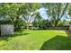 Wide shot of the spacious backyard featuring lush green grass and mature trees at 3663 Kline N Dr, Indianapolis, IN 46226