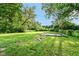 View of the backyard featuring lush greenery, a concrete pad, and wooded surroundings at 3938 N Grand Ave, Indianapolis, IN 46226