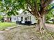 A mature tree compliments this cozy home featuring white siding and freshly painted trim at 405 N Bradley Ave, Indianapolis, IN 46201