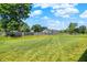 Expansive backyard with lush green grass, mature trees, and a wooden fence providing privacy at 5120 Woodhurst Ln, Indianapolis, IN 46239