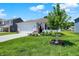 Lovely home with a well-maintained lawn, a young tree, and colorful flower arrangements enhancing its appeal at 5120 Woodhurst Ln, Indianapolis, IN 46239