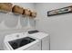 Well-organized laundry room with modern white appliances and baskets on a shelf at 5120 Woodhurst Ln, Indianapolis, IN 46239