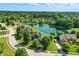 Aerial view of homes surrounding a pond featuring a fountain, showcasing the community layout and green spaces at 5761 Coopers Hawk Dr, Carmel, IN 46033