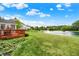 Backyard with pond view, featuring a wooden deck and lush green lawn leading to the water's edge at 5761 Coopers Hawk Dr, Carmel, IN 46033
