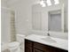Bright bathroom features a cherry wood vanity, toilet, and shower with decorative curtains at 5761 Coopers Hawk Dr, Carmel, IN 46033