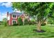 A two-story red brick home is seen from the front yard and boasts professional landscaping at 5761 Coopers Hawk Dr, Carmel, IN 46033