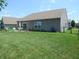 Expansive backyard with green grass, a patio set, and a black chain-link fence at 7232 Moultrie Dr, Indianapolis, IN 46217
