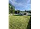 Expansive backyard with a green lawn, patio, playset, and pool, enclosed by a white fence at 8323 Lake Tree Ln, Indianapolis, IN 46217