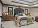 Beautiful primary bedroom featuring a decorative headboard, tray ceiling, and stylish furnishings at 8423 Mud Creek Rd, Indianapolis, IN 46256