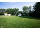 A grassy backyard with trees, lawn and sheds at 8514 Midsummer Dr, Indianapolis, IN 46239