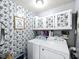 Unique laundry room features wallpaper, cabinets, and white washer and dryer at 1039 Eastlawn Dr, Whiteland, IN 46184