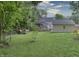 Green backyard with a deck, house and garage behind a fence, and landscaped borders at 115 Northshore Blvd, Anderson, IN 46011