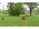 Lush backyard with a firepit area, mature trees, and well-manicured lawn at 115 Northshore Blvd, Anderson, IN 46011