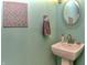 Contemporary powder room featuring a pedestal sink, decorative mirror, and unique wall art at 115 Northshore Blvd, Anderson, IN 46011