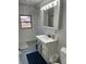 Bright bathroom with white vanity, patterned accent wall, and a window view of the outdoors at 118 S Swain St, Ingalls, IN 46048