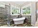 Bathroom featuring a standalone tub, glass shower, and large windows with plants at 1284 N Letterman Rd, Paragon, IN 46166