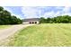 Exterior view of the home highlighting the three-car garage, gravel driveway, and pristine lawn at 1284 N Letterman Rd, Paragon, IN 46166