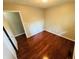 A vacant bedroom featuring hardwood floors, tan walls, and a door to another room at 1345 S Biltmore Ave, Indianapolis, IN 46241