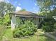 Modest single-story home with vintage architectural details surrounded by overgrown foliage at 1816 E Highland Ave, Muncie, IN 47303