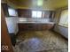 Dated kitchen with worn cabinets, peeling wallpaper, and worn flooring at 1816 E Highland Ave, Muncie, IN 47303