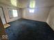 Spacious living room needing renovation with worn blue carpet and outdated fixtures at 1816 E Highland Ave, Muncie, IN 47303