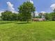 Expansive front yard featuring a large tree, lush grass, and a red barn in the background at 2000 Hawthorne Dr, Plainfield, IN 46168
