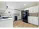 This kitchen features sleek, white cabinets and modern black appliances, with wood-look flooring at 212 N 13Th St, Elwood, IN 46036
