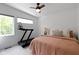 Bright bedroom featuring a ceiling fan, large windows, a treadmill and a queen bed with peach and neutral bedding at 2326 Prospect St, Indianapolis, IN 46203