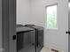 Modern laundry room with a window, modern black appliances, gray walls and white trim and light wood flooring at 2326 Prospect St, Indianapolis, IN 46203