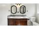 Bathroom with double sink vanity, decorative mirrors, and white toilet at 4023 N Arlington Ave, Indianapolis, IN 46226