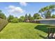 Large grassy backyard featuring a storage shed, bordered by a wooden fence and mature trees at 452 N Fenton Ave, Indianapolis, IN 46219