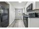 Well-lit kitchen with white cabinetry, black appliances, and laminate flooring at 452 N Fenton Ave, Indianapolis, IN 46219