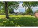 Spacious backyard with mature trees, green lawn, and a charming fire pit area, perfect for outdoor activities at 4625 Beth Ann Dr, Indianapolis, IN 46221