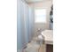 Bright bathroom with white fixtures, light blue shower curtain, and decorative shelves at 4625 Beth Ann Dr, Indianapolis, IN 46221