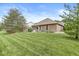 Expansive backyard with lush greenery, patio, and a brick home with yellow window shutters at 5659 Augusta Woods Dr, Plainfield, IN 46168