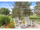 Relaxing patio area with rocking chairs, flowering plants, and a peaceful backyard setting at 5659 Augusta Woods Dr, Plainfield, IN 46168