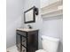 Bathroom with a dark vanity, white toilet, and wall shelving at 615 Udell St, Indianapolis, IN 46208