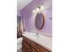 A vibrant purple bathroom features a wooden-framed mirror and traditional vanity at 619 Cahill Ln, Indianapolis, IN 46214