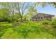 View of the grassy backyard, with the gray-sided house on the right side of the frame at 9319 Rochelle Dr, Indianapolis, IN 46235